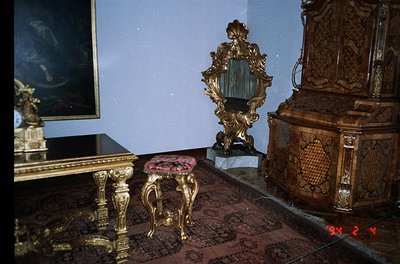 Baroque-style interior featuring ornate gold-accented furniture: intricately carved wooden cabinet with floral motifs, gilded...