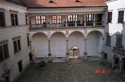 Historic courtyard with Renaissance-style arches and stone balustrades. Two-story colonnade frames a gravel-paved central are...