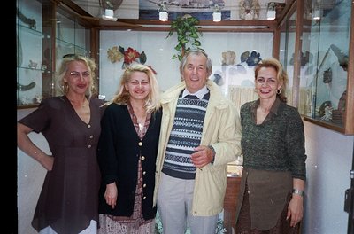 Four individuals pose indoors in a well-lit, decorative setting. The man wears a striped sweater and light jacket, while the ...