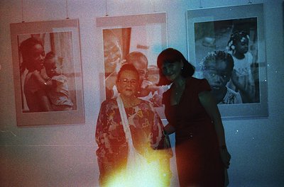 Vintage exhibition featuring framed black-and-white portraits on a dimly lit wall, likely from the 1960s–1970s. Central figur...