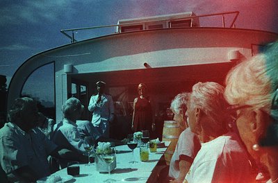 Vintage cruise ship dining hall with mid-century modern curved ceiling. Passengers in 1960s attire—men in suits, women in dre...