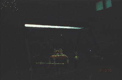 Vintage film grain overlay of a dimly lit indoor scene with a neon sign and decorative Christmas tree elements. The blurred, ...