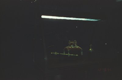 Vintage neon sign featuring a crown and ornate letters, likely "Crown" or "Crown Inn." Glowing amber-yellow against dark back...