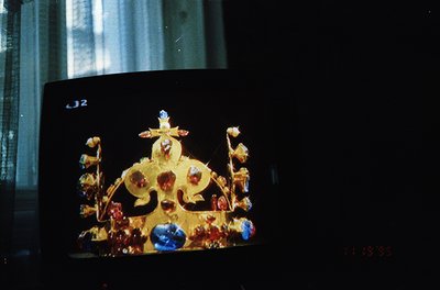 Vintage close-up of an ornate, gold-toned crown adorned with red and blue gemstones, likely a religious or ceremonial artifac...