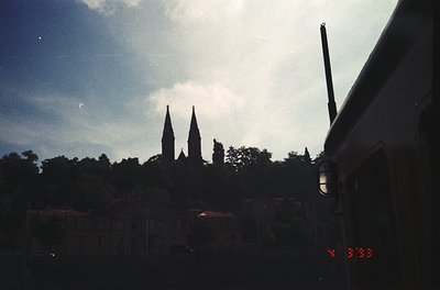 Silhouetted twin spires framed by vintage train window, likely 1950s–1970s. Distinctive Gothic architecture suggests European...