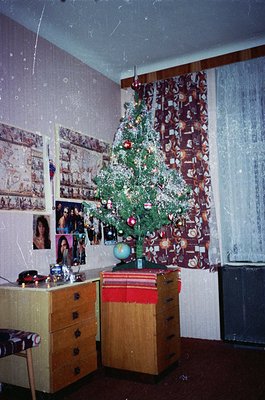 Vintage interior featuring a modestly decorated Christmas tree beside a wooden desk with vintage globe and stacked books. Col...
