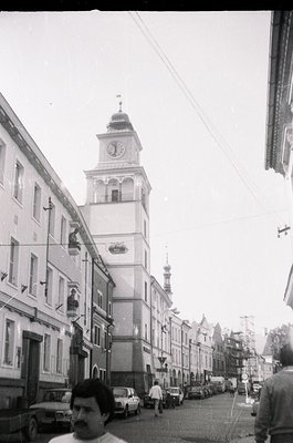 Prominent clock tower with ornate dome and Soviet-era architectural details dominates a narrow European street. Mid-20th cent...