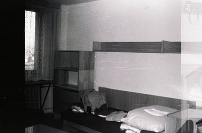 Vintage mid-century bunk bed setup in a minimalist bedroom, featuring built-in shelves above and a single bed below. Plain wa...