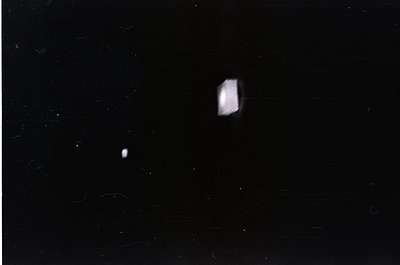Vintage black-and-white photo of two faint, overexposed light sources against a dark background—likely a moon and planet in n...