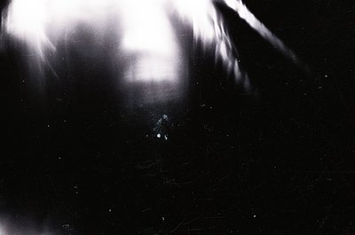 High-contrast black-and-white portrait with dramatic lighting, capturing a close-up of a person’s face obscured by strong bac...