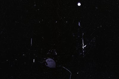 High-contrast nighttime shot of shattered glass fragments under moonlight. Visible cracks and debris suggest a broken surface...