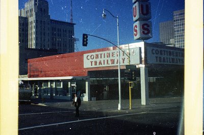 Vintage urban scene featuring a **Continental Trailways bus station** with bold red signage and "USS" neon sign. Mid-century ...