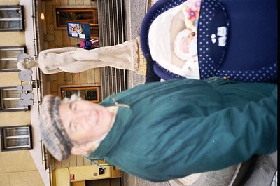 Vintage mirror selfie of two individuals in an indoor hallway, likely a 1980s-1990s setting. The person in foreground wears a...