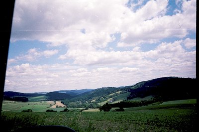Vintage landscape shot of rolling green hills under dramatic, billowing clouds. Rolling terrain with scattered trees and open...