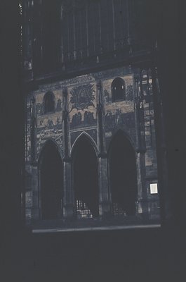 Gothic-style stained glass window featuring three pointed arches with intricate floral and geometric patterns. Likely from a ...