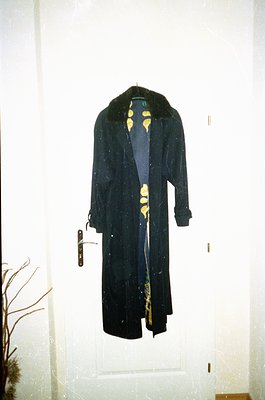 Vintage long coat with black fur collar and yellow floral lining, hung on a brass door handle. Mid-century design suggests 19...