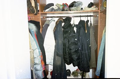 Vintage closet displaying utilitarian outerwear—heavy-duty jackets, raincoats, and insulated parkas hung on a rustic metal ro...
