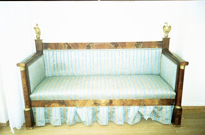 Antique wooden bench with ornate brass eagle finials, upholstered in vintage striped fabric. Dark wood grain and aged patina ...