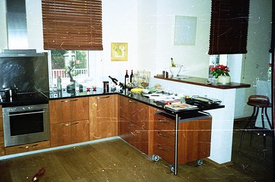Mid-century modern kitchen with wooden cabinetry and marble countertops, featuring a built-in oven and roll-out prep station....