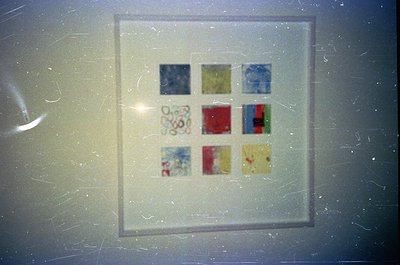 Vintage 35mm slide frame featuring nine small, faded color patches—likely test strips or artistic samples. Patterns include f...