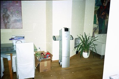 Vintage office space with mid-century design elements: a cylindrical air conditioner unit, a potted plant, and a cardboard bo...