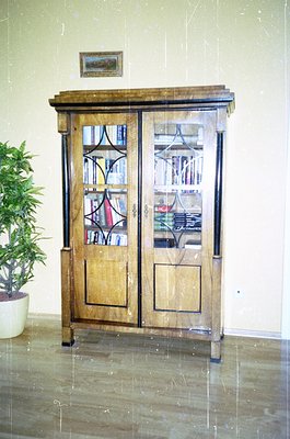 Antique wooden cabinet with stained-glass doors featuring geometric patterns, likely 19th-century European design. Dark trim ...