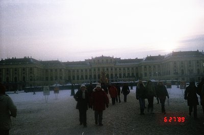 Neoclassical palace courtyard in winter, likely **Schönbrunn Palace, Vienna, Austria**. Frost-covered ground and low winter l...