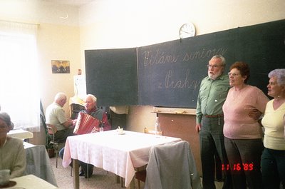 Vintage indoor gathering in a classroom setting, dated **1983**. Six adults—four men and two women—engage in a folk music ses...
