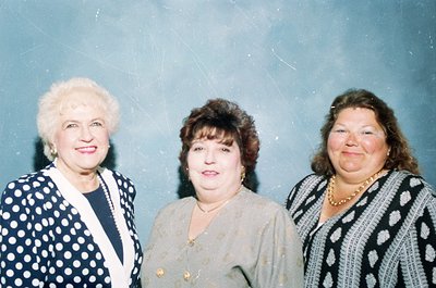 Three women in formal attire pose indoors, likely mid-1990s to early 2000s. Left: white-blonde hair, dark polka-dot blazer wi...