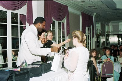 Vintage banquet hall scene featuring a male waiter in white uniform handing a bridal bouquet to a bride in 1970s attire. Purp...