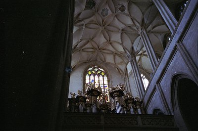 Gothic-style cathedral interior with ribbed vaulted ceiling and stained-glass window. Ornate altar featuring carved wood and ...