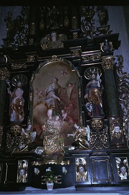 Baroque-style altar with gilded woodwork, featuring central fresco of Virgin Mary and child flanked by angels and saints. Int...