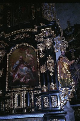 Baroque-style altar featuring gilded woodwork, intricate carvings, and a central religious painting depicting saints. Ornate ...