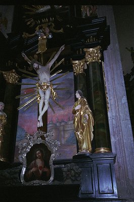 Baroque-style altar featuring a crucifixion scene with gilded accents. Central crucifix with radiating light rays, flanked by...
