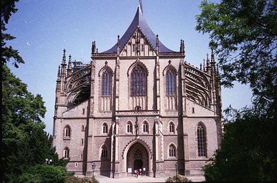 Gothic-style cathedral with pointed arches, ribbed vaults, and a steeply pitched roof, framed by lush greenery. Likely 14th–1...