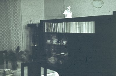 Vintage black-and-white shot of a mid-century bar counter with mirrored shelves displaying stacked glasses and bottles. A bar...