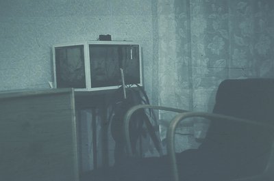 Vintage interior featuring a double-monitor setup on a wooden desk, likely from the 1970s–1980s. Monochrome CRT screens displ...