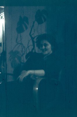 Vintage sepia-toned shadow play on a window, capturing a seated figure with a hat and coat. Light filters through, creating a...