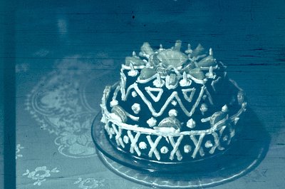 Vintage sepia-toned cake adorned with geometric icing patterns and decorative sugar accents, likely a wedding or ceremonial d...
