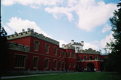 Neoclassical-style red-brick building with crenellated roofline, likely a historic estate or government complex. Symmetrical ...