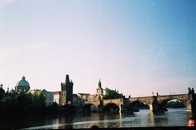 Iconic Charles Bridge spanning Prague’s Vltava River, showcasing Gothic towers and domes of historic Prague Castle in backgro...