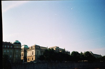 Neoclassical building with domed roof and symmetrical façade, likely a historic institution or government edifice. Lush green...