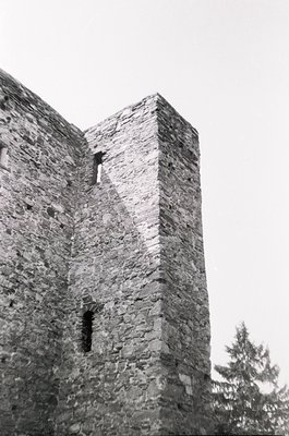 Medieval stone tower with rough-hewn blocks, featuring narrow slit windows and a rectangular base. Likely European, possibly ...