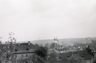 Vintage black-and-white urban landscape featuring a domed church with a tall spire in the background, surrounded by low-rise ...