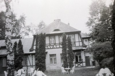 Vintage black-and-white photo of a two-story building labeled "CAVARA" in Art Nouveau-style lettering, featuring gabled roofs...