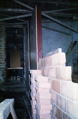 Industrial brick chimney base with exposed red metal support beams and partial brickwork collapse. Likely a mid-20th century ...