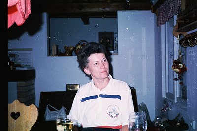 Vintage indoor portrait of a woman in a retro sports jersey (1970s-80s style) seated at a table with wine glasses. Lighting s...