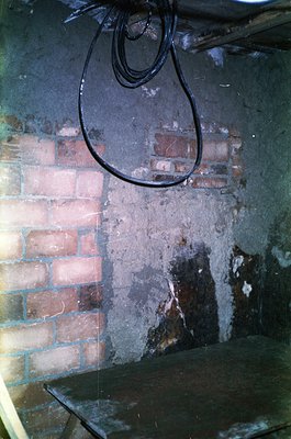Vintage industrial interior featuring a rusted metal wall-mounted lamp with a cracked glass shade. Exposed brickwork with fad...