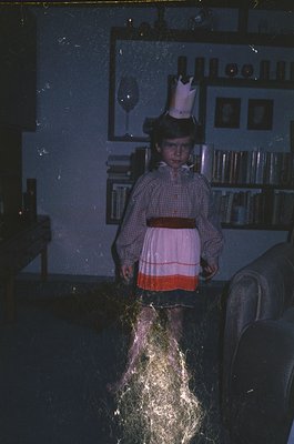 Vintage indoor portrait of a child in a princess dress with a crown, holding a sparkler. Warm lighting and blurred motion cap...