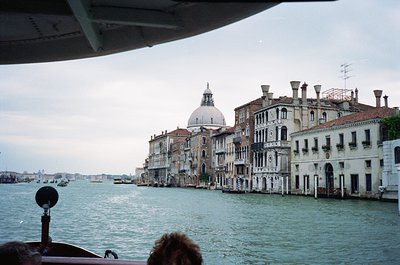 Venetian canal scene showcasing historic palazzos with arched windows and domed church in background. Waterfront architecture...